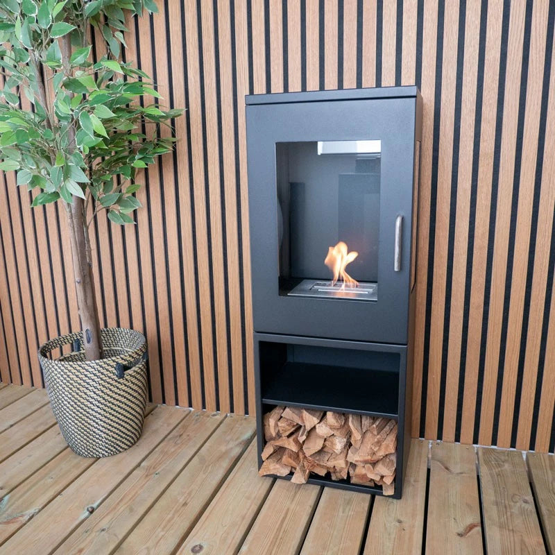 Cheyenne bioethanol stove fireplace against a slatted wood wall, lit flame, with a potted plant