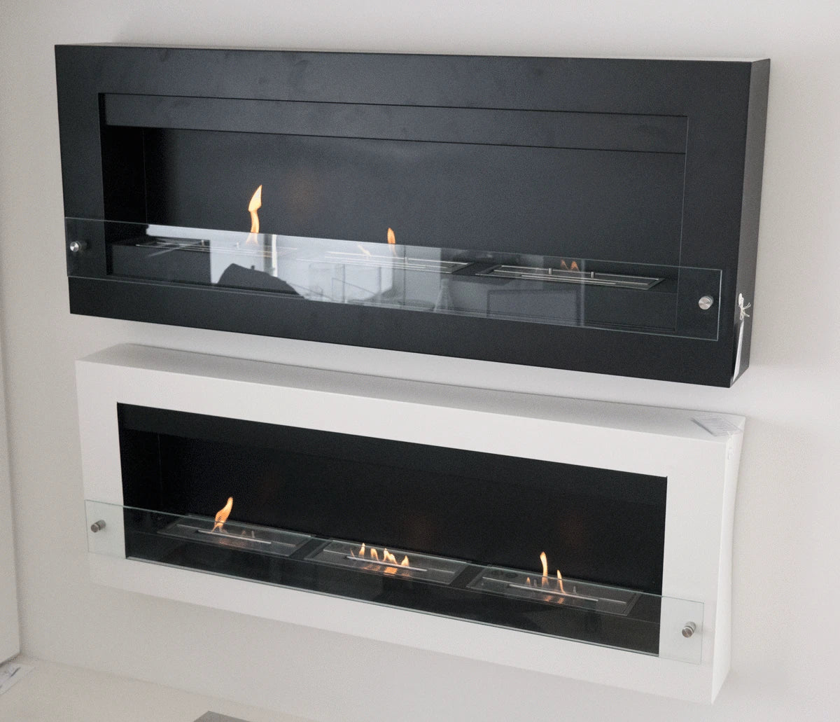 Black and white XL wall-mounted bioethanol fireplaces mounted side by side for comparison, angled showroom photo