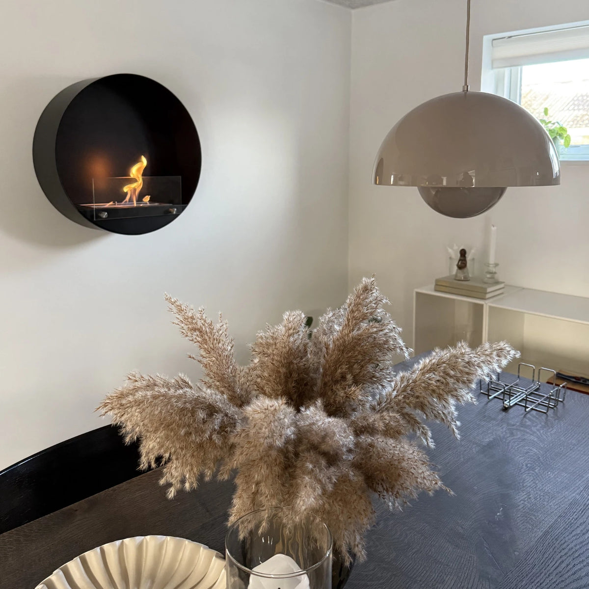 Delaware black round bio fireplace mounted above a dining table with pampas grass