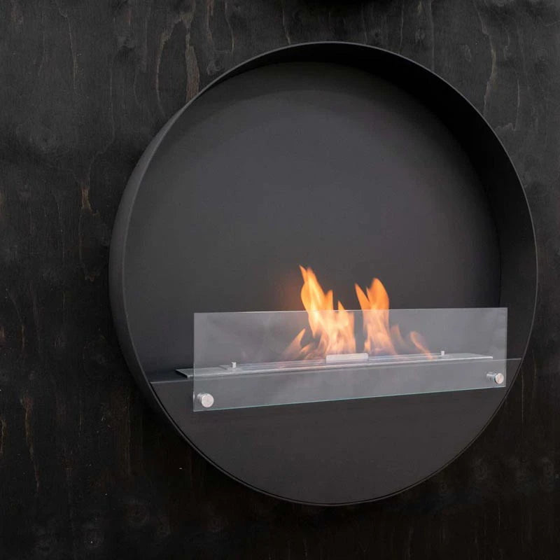 Delaware XL black round bio fireplace mounted on a dark wood-textured wall, lit with a realistic flame