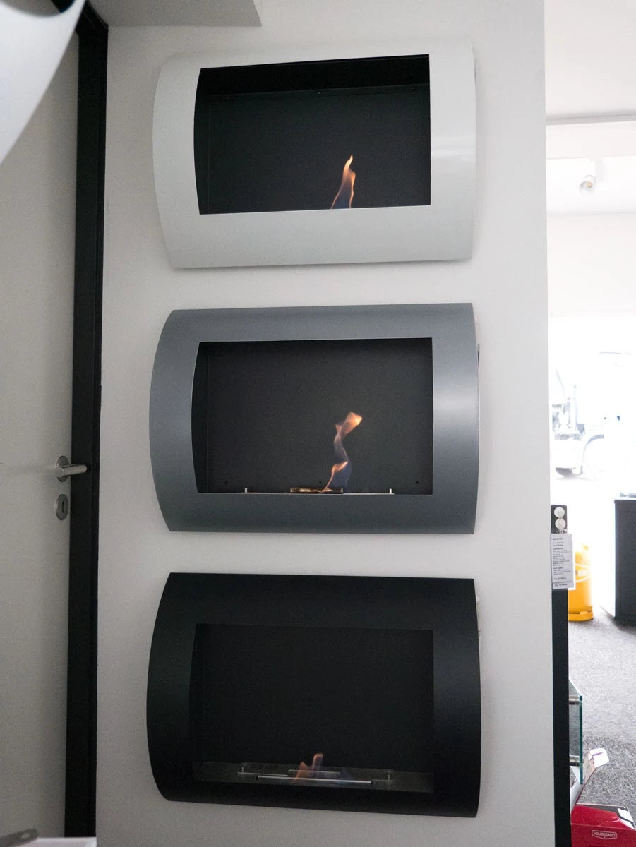 Three ScandiFlames wall-mounted bioethanol fireplaces in white, silver and black mounted side by side in a showroom display