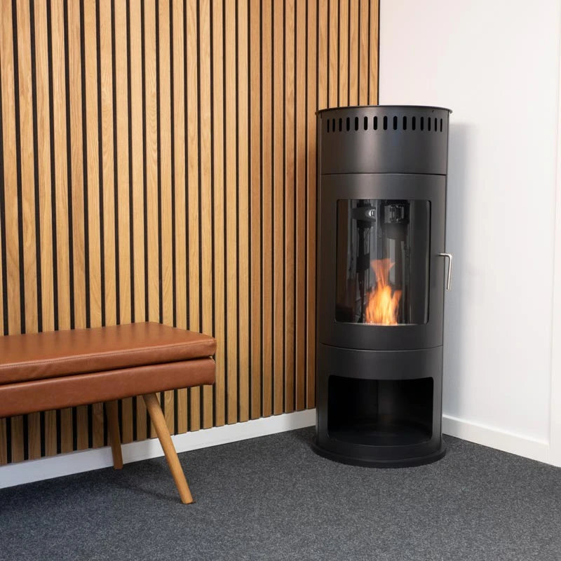 Washington black bioethanol stove lit in a showroom setting with a wood slat wall and leather bench