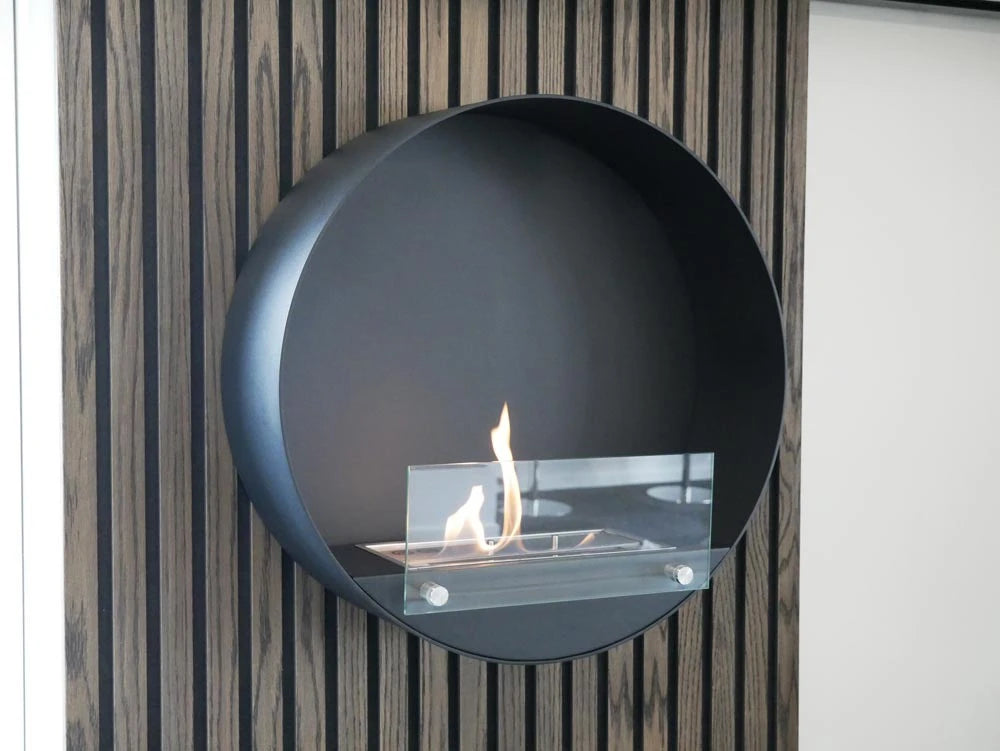 Delaware black round bio fireplace on a slatted wood-panelled wall, angled view