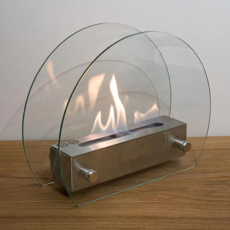 Circular table bioethanol fireplace lit on a wooden surface against a plain wall