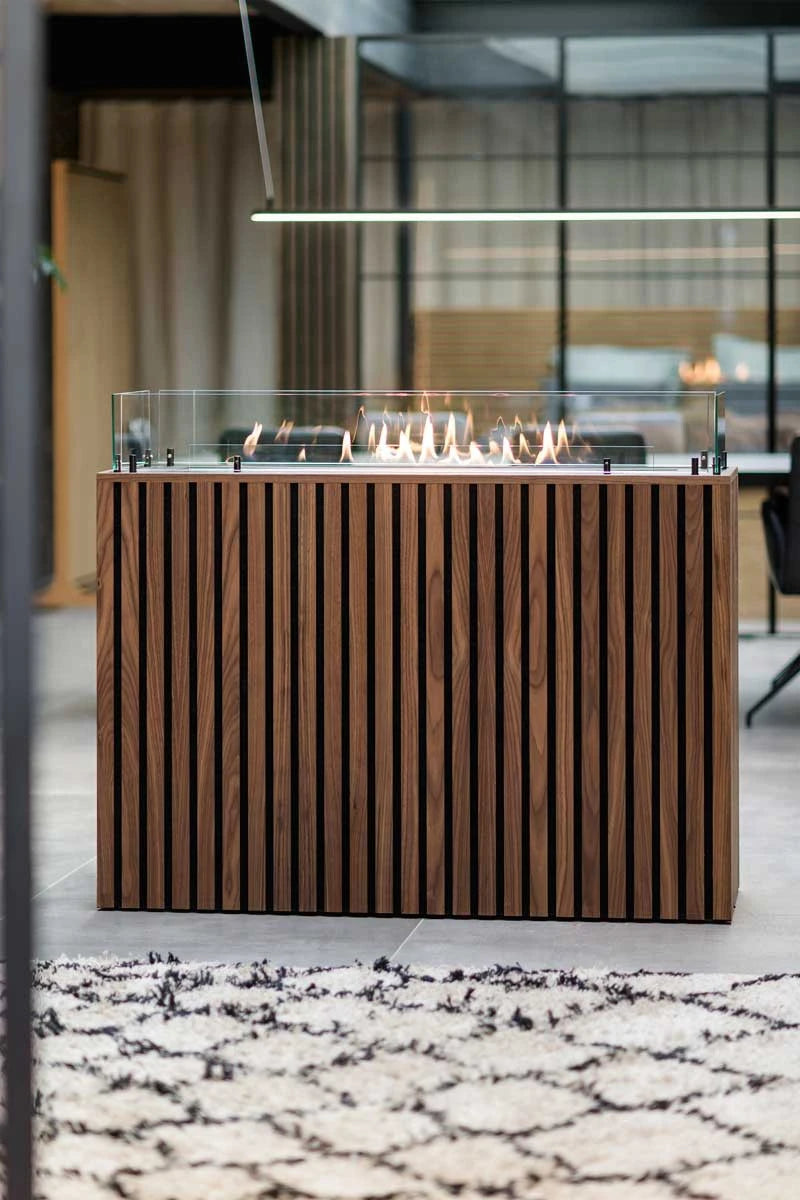 Foco Free 1200 built into a dark walnut wood-slat housing with a lit flame, modern interior