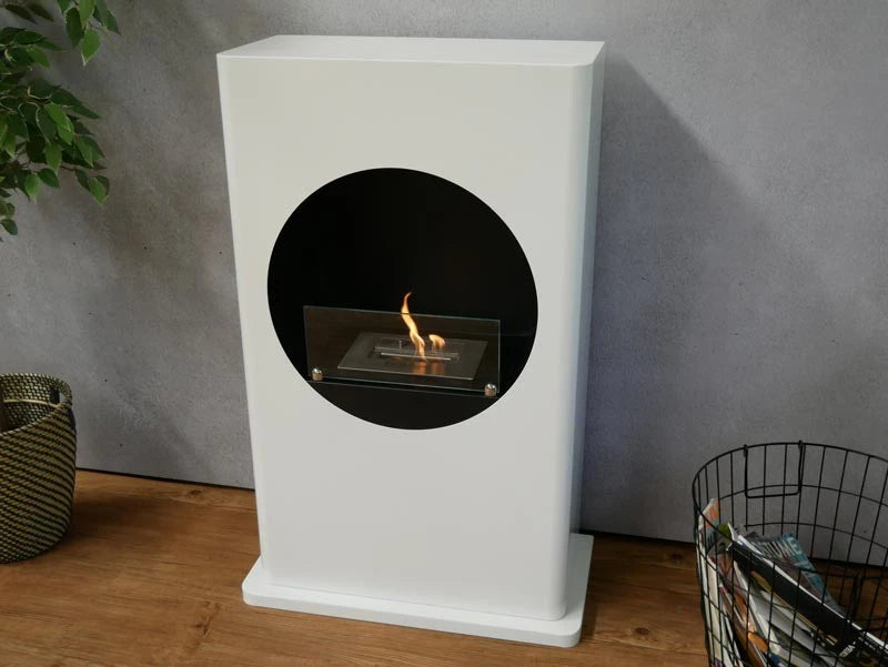 White freestanding bioethanol fireplace with round cutout, angled living room view, lit flame
