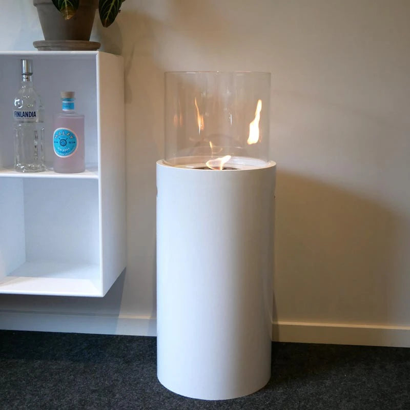 Outdoor white bioethanol fireplace with a lit flame in an indoor living room setting