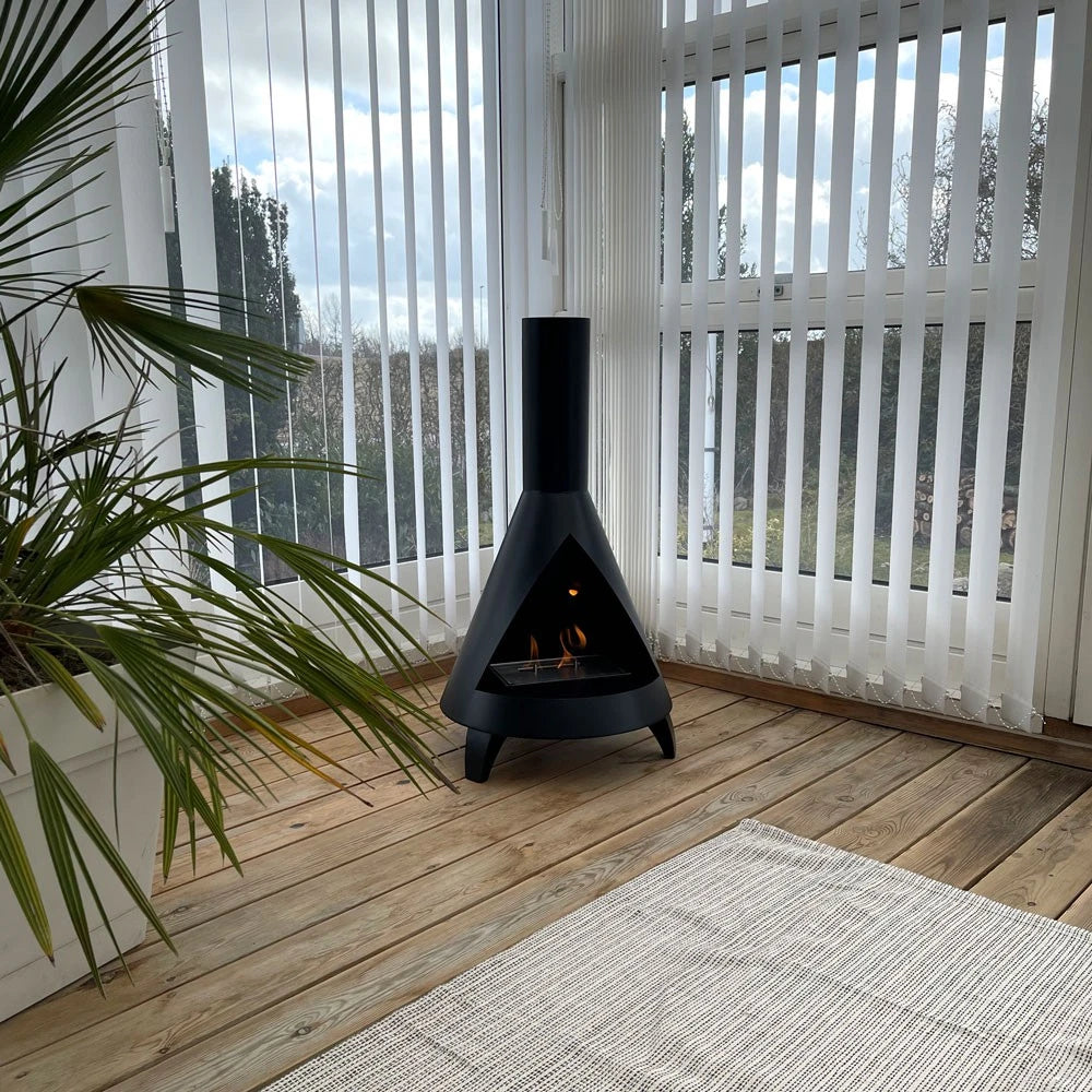 ScandiFlames Salem bioethanol fireplace with a lit flame in a bright conservatory beside a palm plant