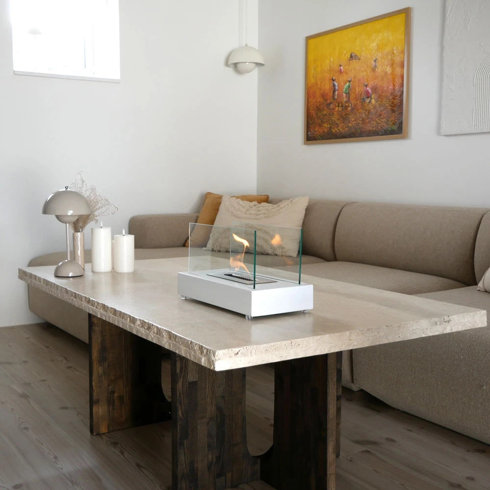 Lambeth white bioethanol fireplace lit on a marble coffee table beside a sofa
