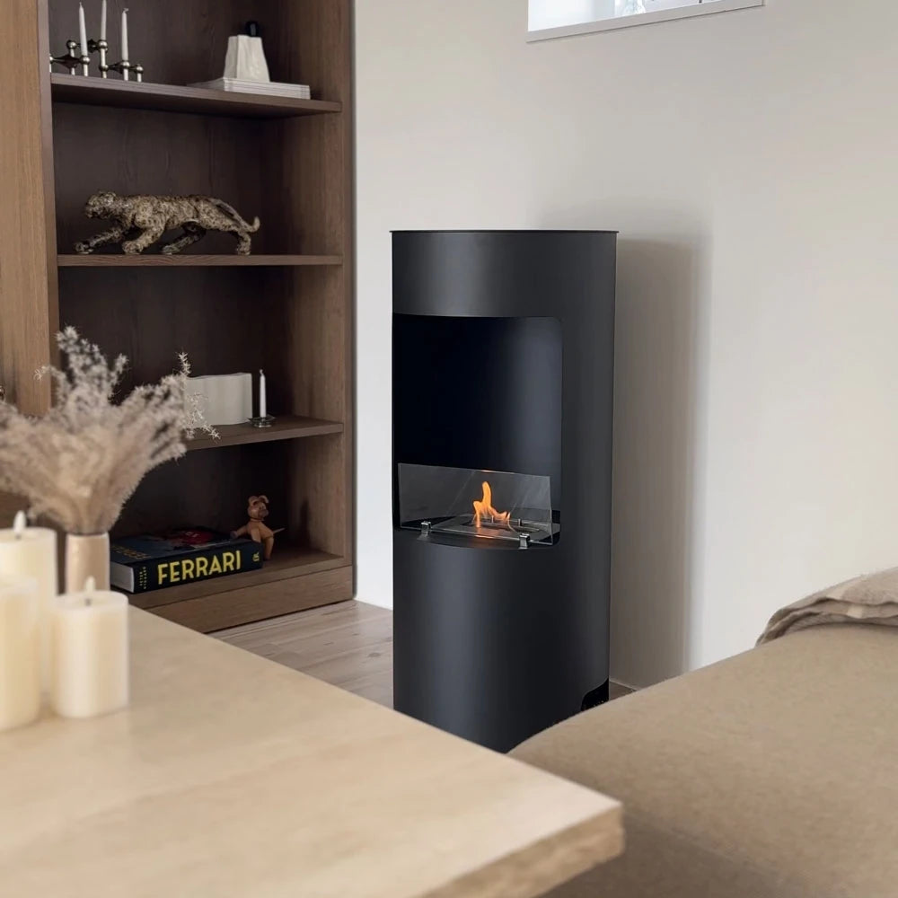 Montgomery black bioethanol fireplace lit in a living room with wooden bookshelf, candles and beige sofa