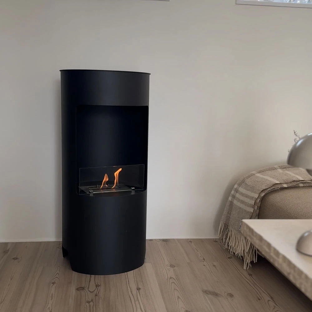 Montgomery black bioethanol fireplace lit in a living room with wood flooring and a beige sofa