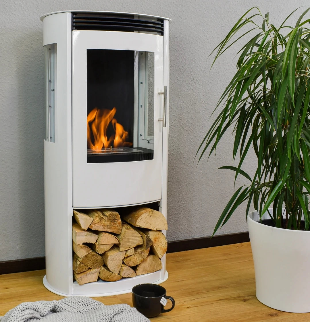 Lincoln white bioethanol stove lit with decorative logs stored underneath and a potted plant beside it