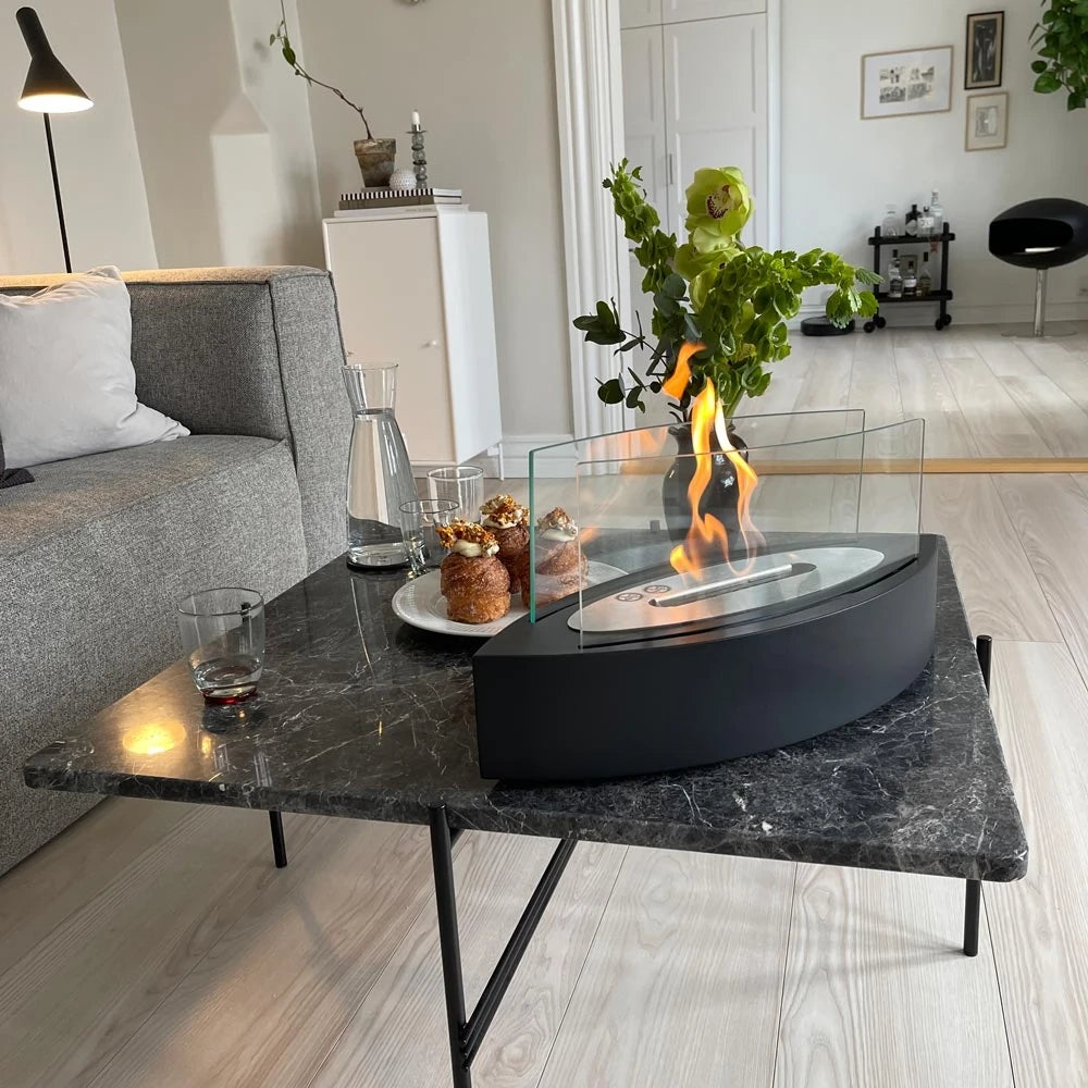 ScandiFlames oval black tabletop bioethanol fireplace lit on a marble coffee table with pastries