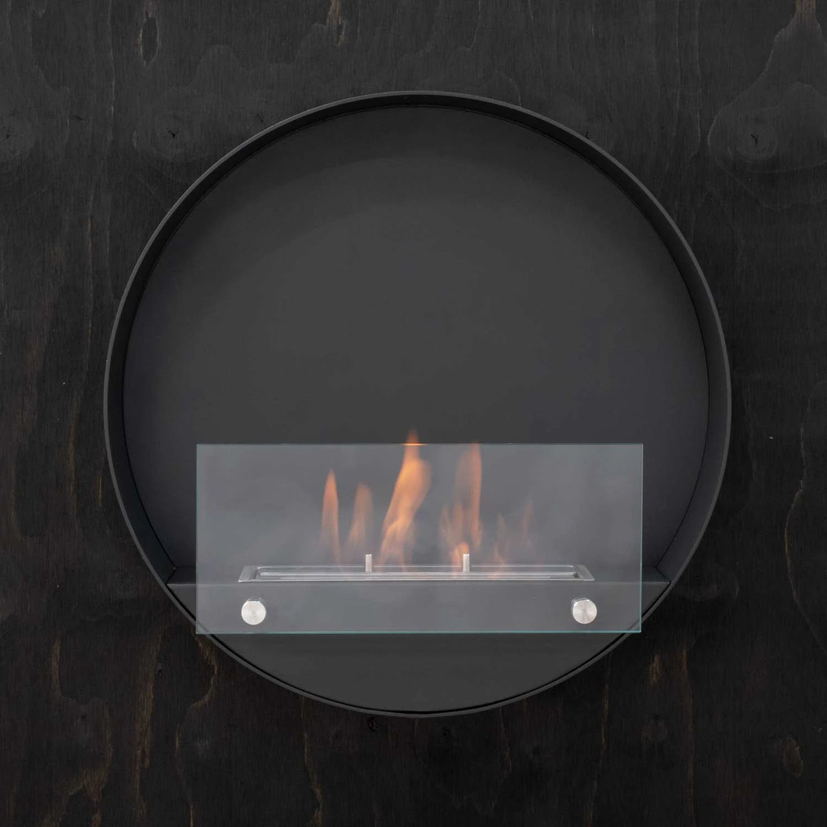 Delaware S black round bio fireplace mounted on a dark wood-textured wall, lit with a realistic flame