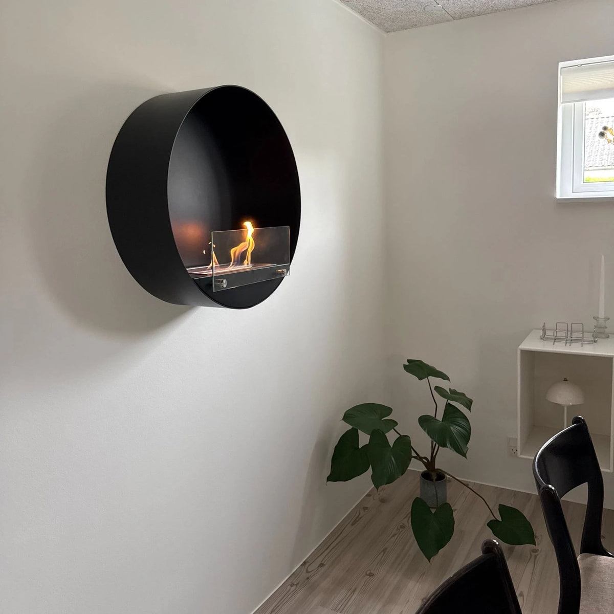 Delaware black round bio fireplace mounted in a corner near a potted plant