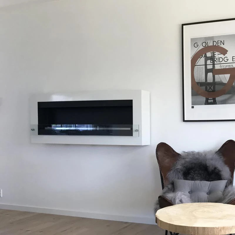 XL wall-mounted white bioethanol fireplace, unlit, styled in a living room with leather wingback chairs and framed wall art